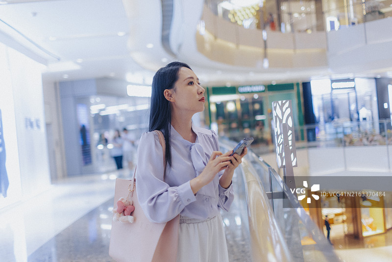 在城市现代购物中心使用智能手机的年轻女商人图片素材