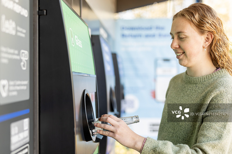 年轻女子使用塑料瓶回收机图片素材