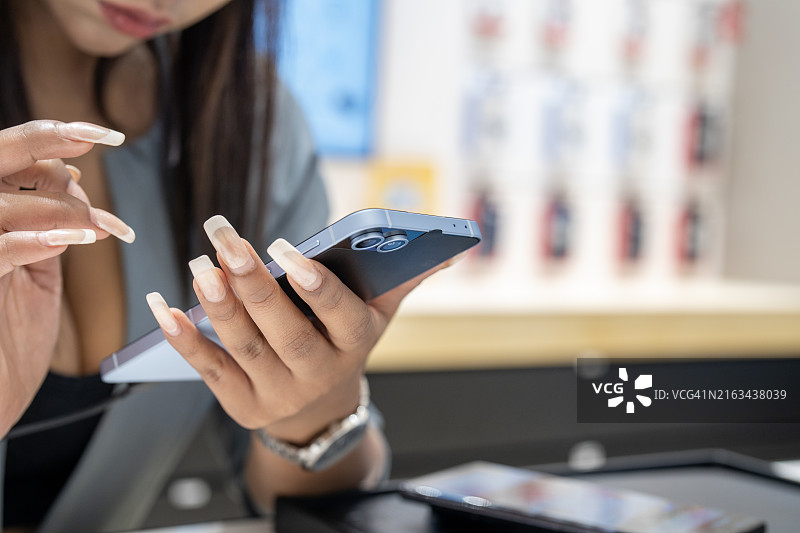 快乐的女人在商店里选择智能手机图片素材