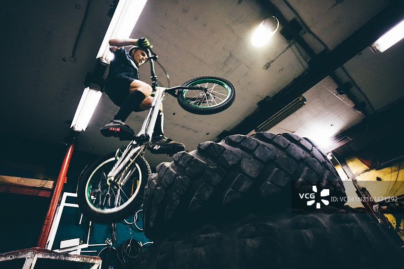 男子在室内表演自行车前轮离地和跳跃图片素材