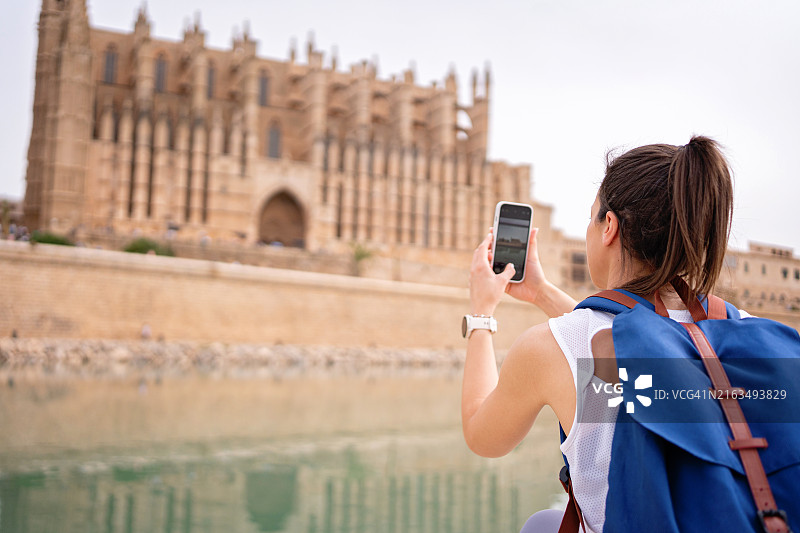 一位年轻女游客在马略卡岛帕尔马拍摄圣玛丽亚大教堂图片素材
