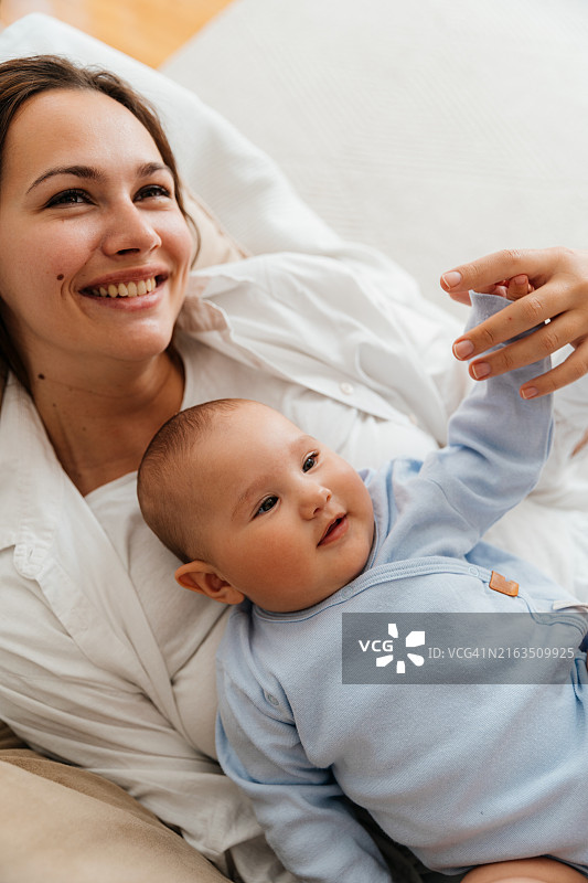 年轻母亲和她的宝宝躺在一起依偎着图片素材