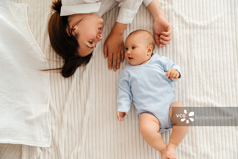 年轻母亲和她的宝宝躺在一起依偎着图片素材