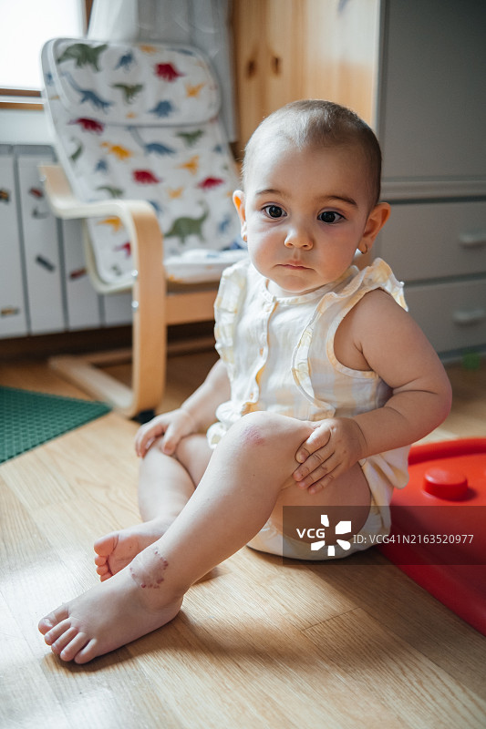 孤独悲伤的一岁女童坐在儿童房地板上图片素材