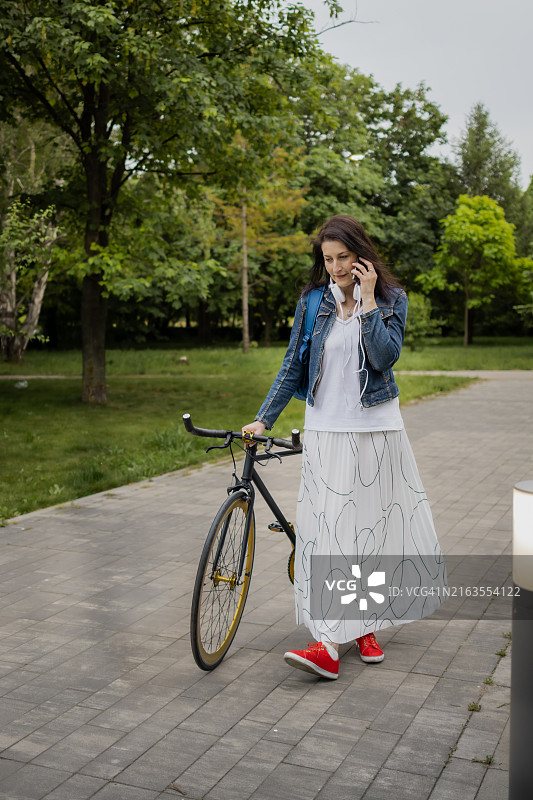 戴着耳机用手机的微笑女通勤者图片素材