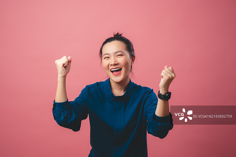 自信微笑并展示拳头的快乐亚洲女性，隔离背景图片素材