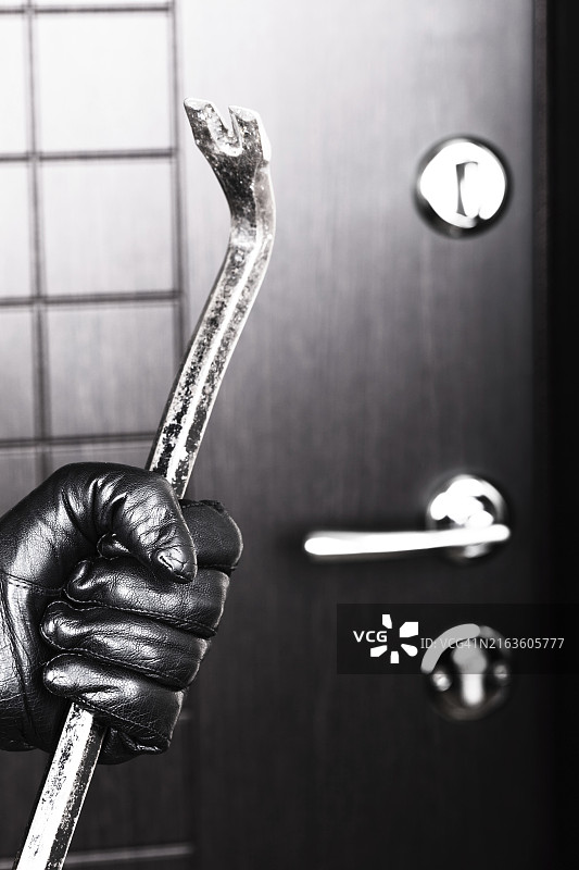 犯罪现场：戴手套的窃贼用金属撬棍撬锁入室图片素材