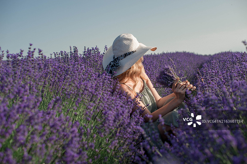 一位年轻美丽的女性在夏天的薰衣草田里。图片素材