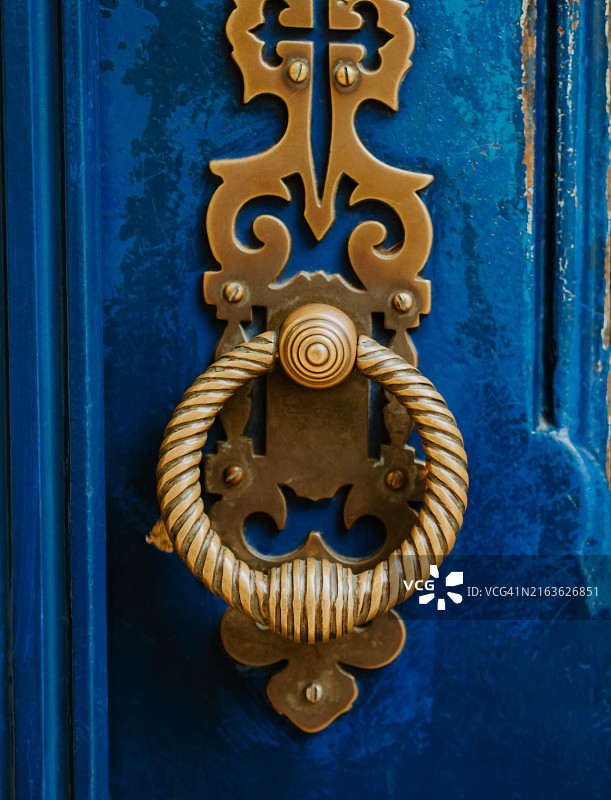 鲜艳蓝色门上华丽的古董黄铜门环特写图片素材