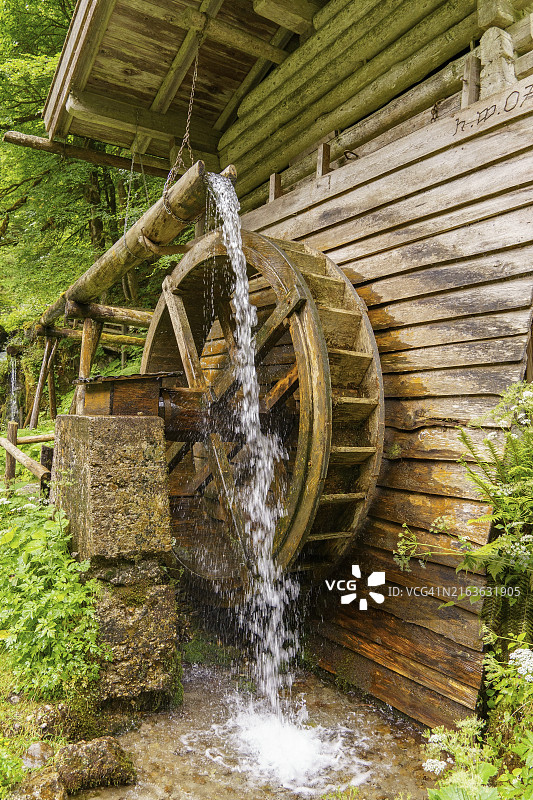 奥地利戈绍森林中，水流过大型磨轮的乡村木制水磨坊图片素材