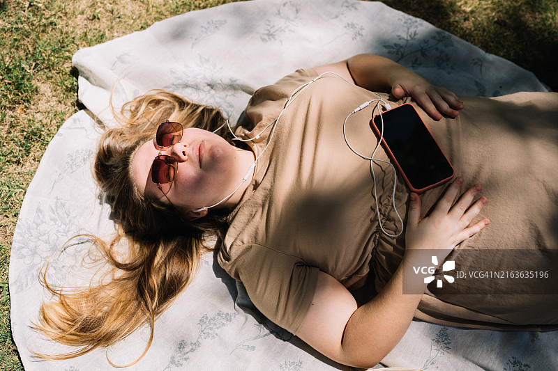女人戴着耳机在公园里放松图片素材