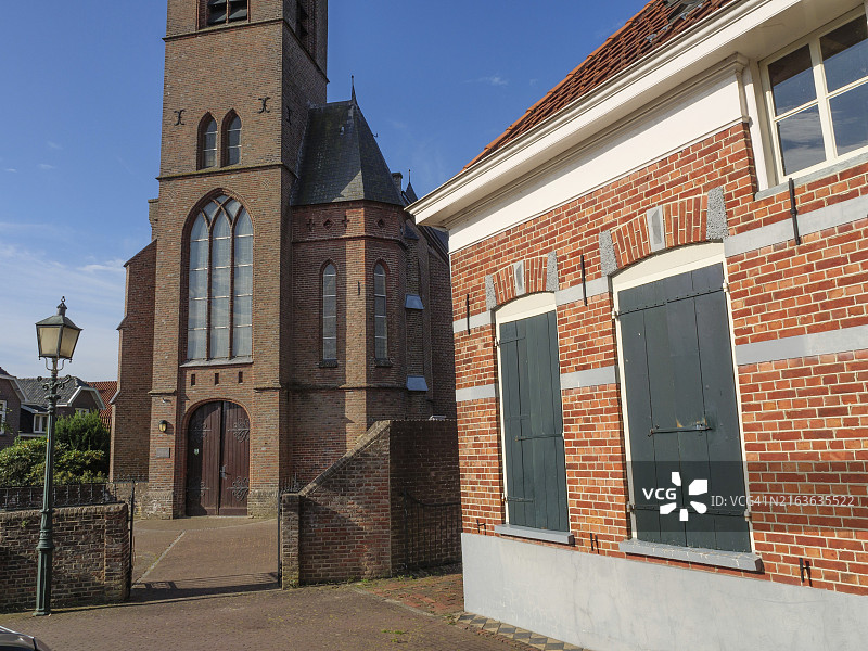 荷兰布雷德福特：教堂塔楼与石制细节，毗邻带绿色百叶窗的古老建筑图片素材