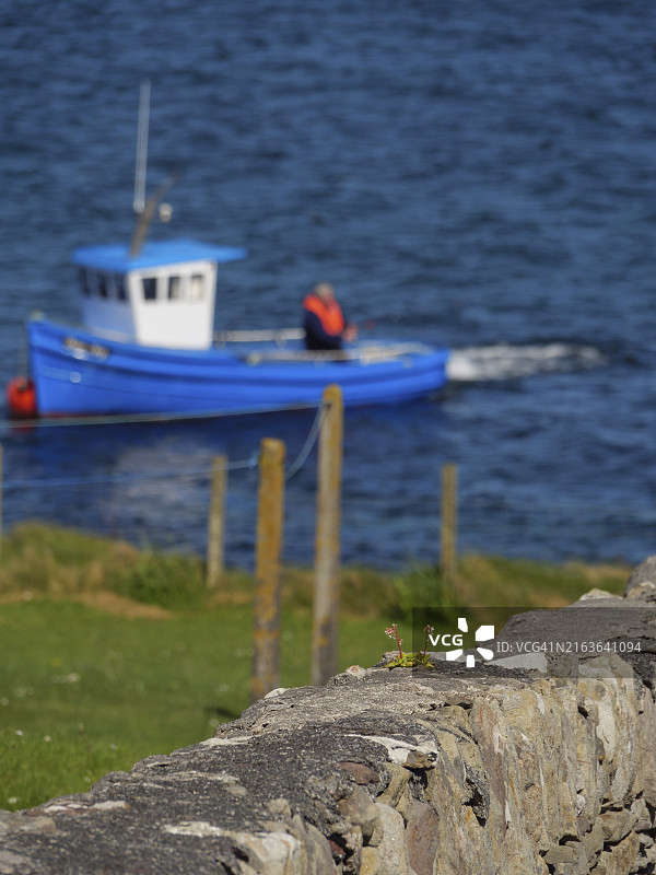蓝色水面上石墙后模糊的渔船和栅栏，勒威克，设得兰群岛，苏格兰，英国，欧洲图片素材