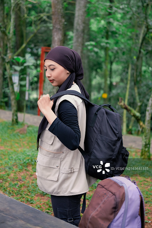 准备探索：年轻女子在城市公园散步时抬起背包图片素材