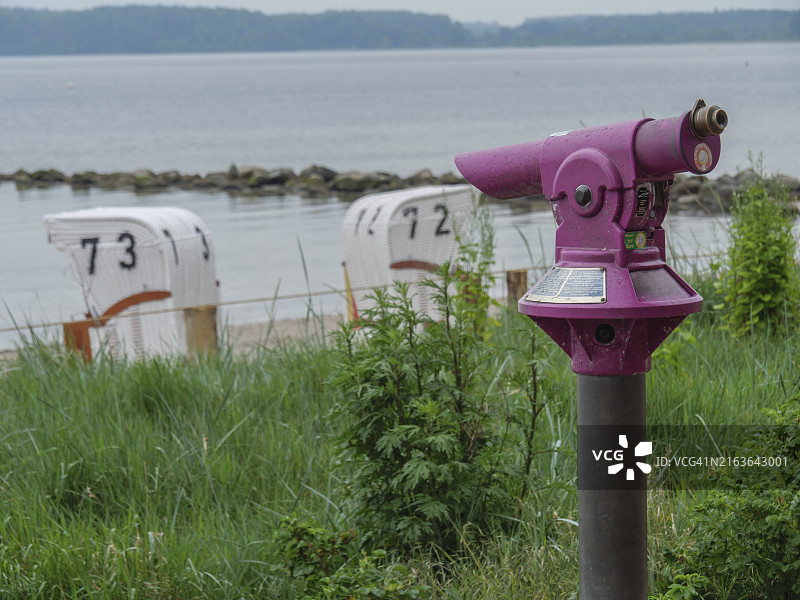 紫色双筒望远镜下的海滩椅和宁静海面，德国石勒苏益格-荷尔斯泰因州埃克尔恩弗尔德图片素材
