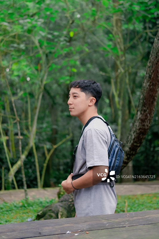 准备去探索：年轻男人拿起背包在城市公园散步图片素材