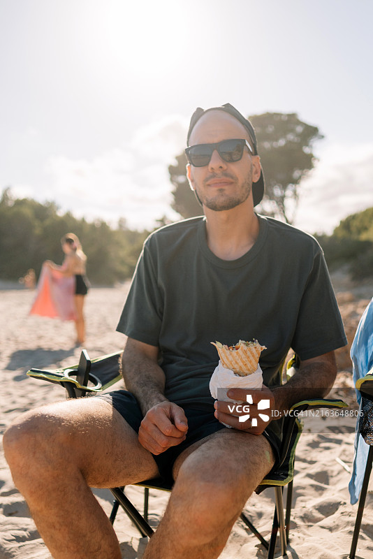 男子坐在海滩的椅子上，手持硬质小麦图片素材