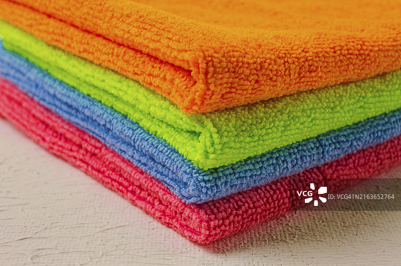 白色桌子上用于清洁房屋的彩色超细纤维抹布图片素材