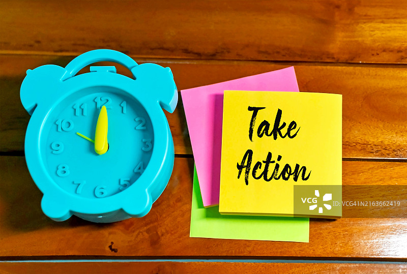 采取行动——在黄色便签纸上，旁边放着一个闹钟图片素材