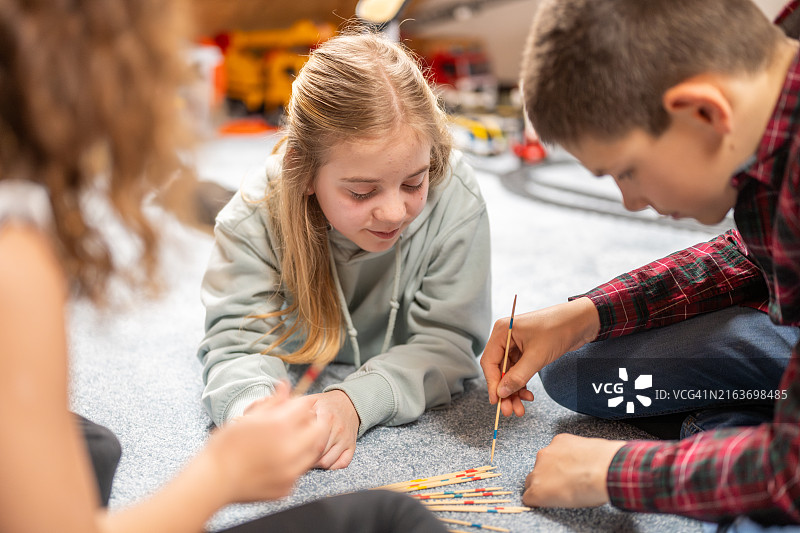 专注玩挑棍游戏的孩子们图片素材