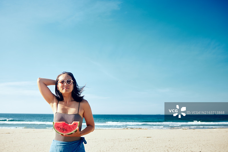 手拿西瓜、迎风撩发的女人肖像图片素材