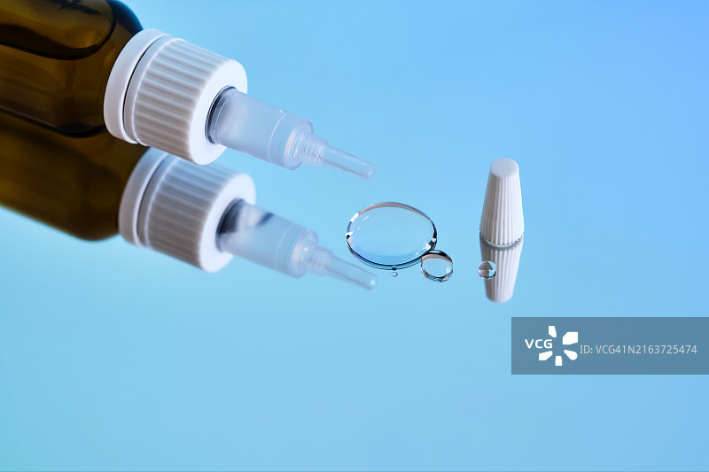 镜面蓝色背景上的滴耳液瓶图片素材