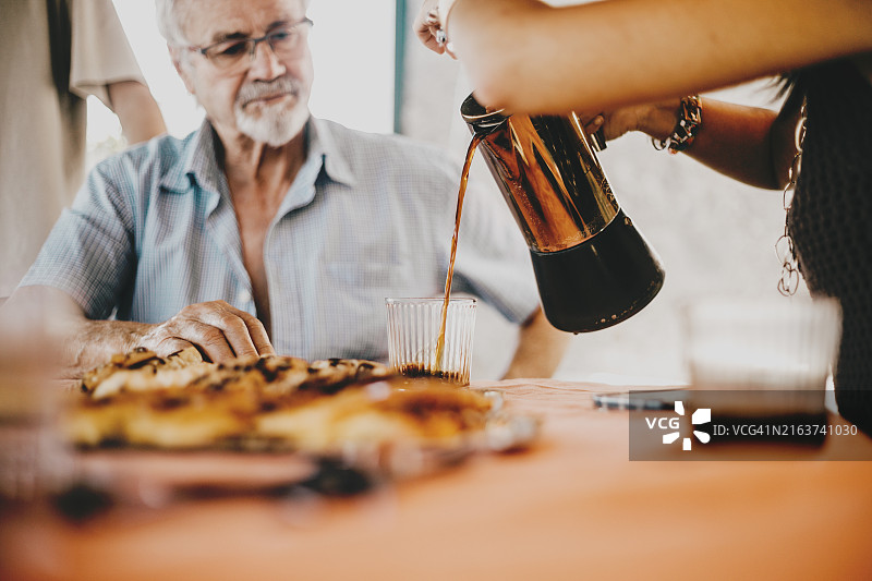 女子将现代铬制水壶中的开水倒入玻璃杯中图片素材