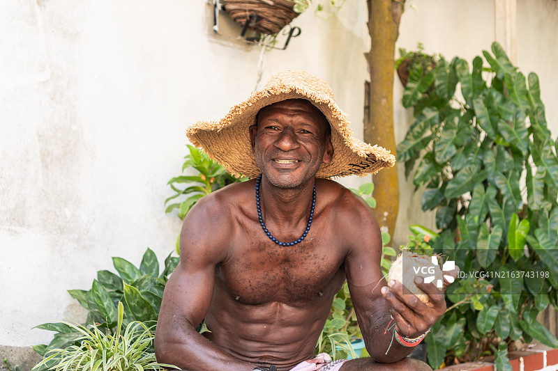 戴草帽手捧椰子的微笑男人图片素材