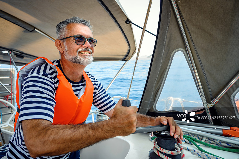 在帆船上使用绞盘的中年男人图片素材