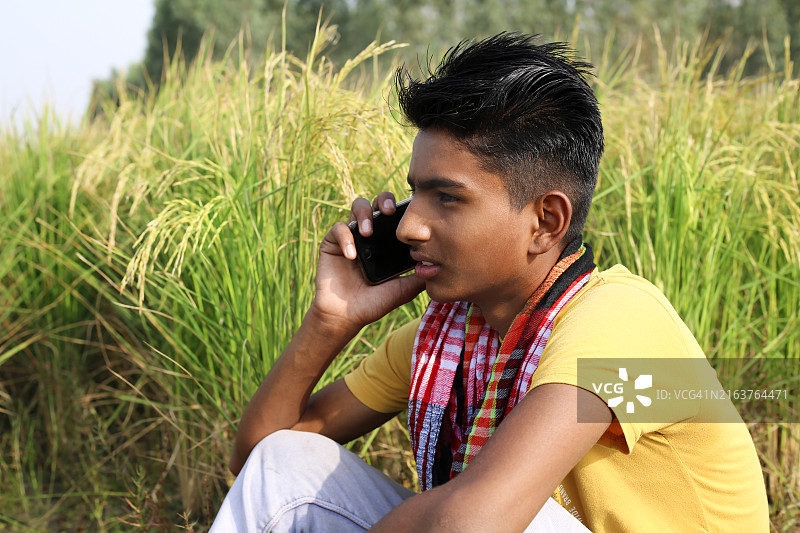 在绿地附近用手机交谈的年轻农民图片素材