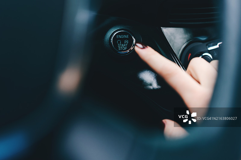 女性伸手启动汽车引擎的特写图片素材
