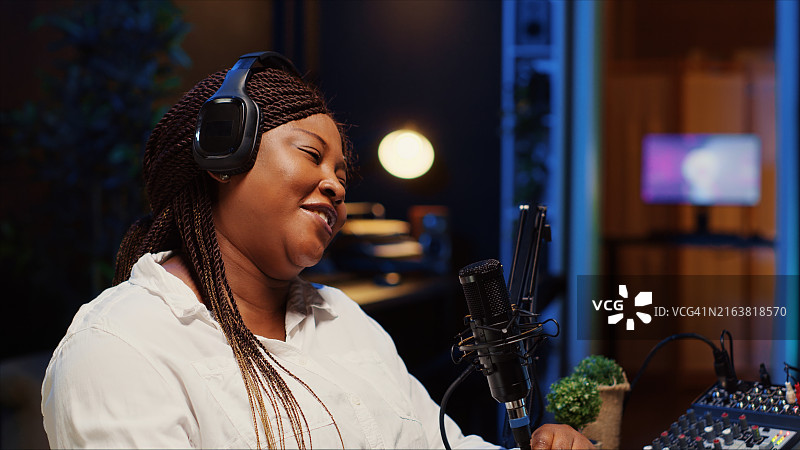 女子录制播客，调整麦克风以确保最佳音质图片素材
