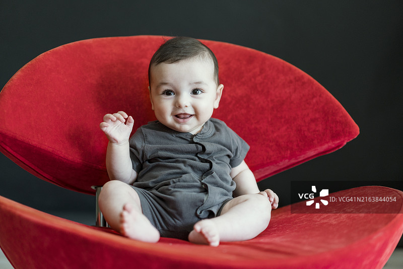 坐在红色扶手椅上的可爱男婴图片素材