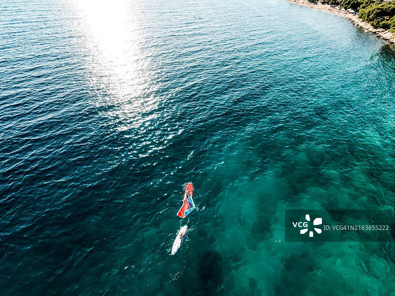 父亲和儿子在平静美丽的海面上玩立式桨板图片素材