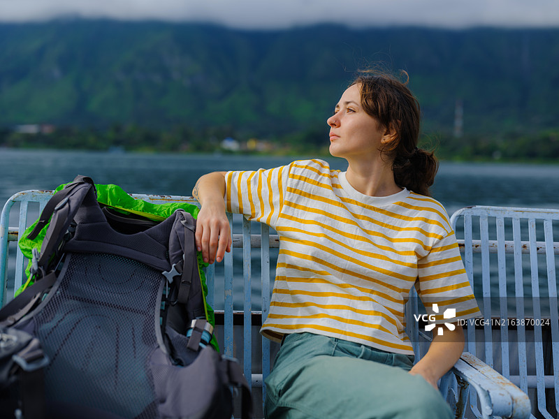 快乐的女人在印度尼西亚苏门答腊岛多巴湖上乘坐渡轮旅行图片素材