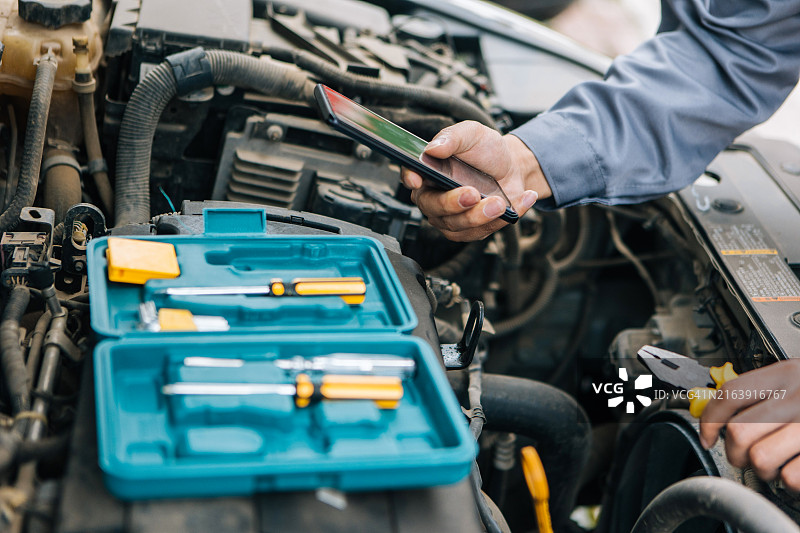 技工身穿工作服检查和修理汽车图片素材