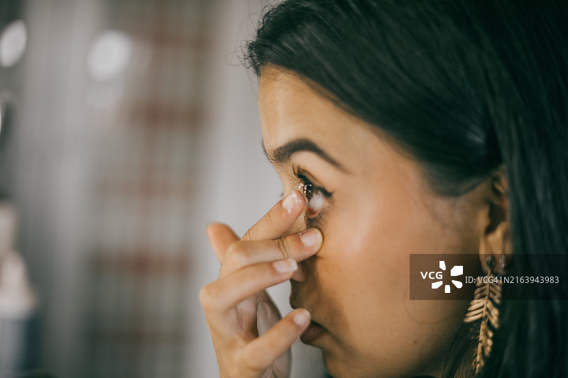 年轻女人在家中佩戴隐形眼镜图片素材