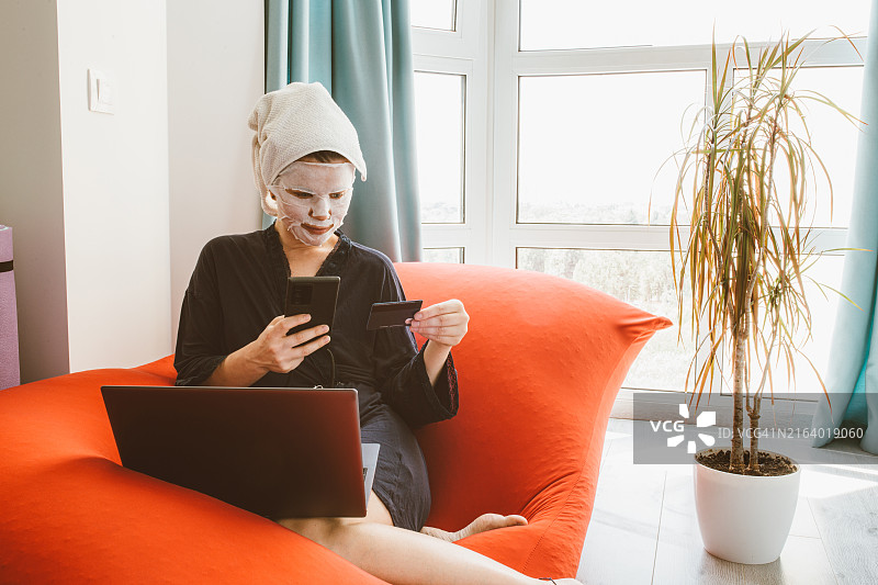 在家敷着面膜进行网购的年轻女人图片素材