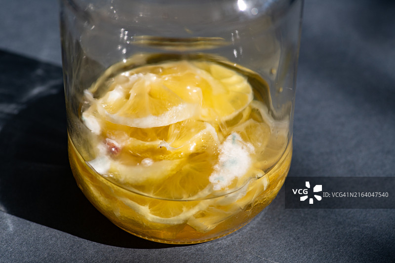 黄色背景玻璃罐中的发霉柠檬片图片素材