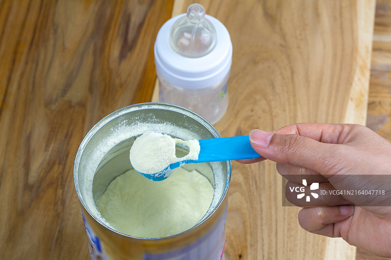 淡色背景上的奶粉和蓝色勺子，婴儿奶粉和奶瓶图片素材