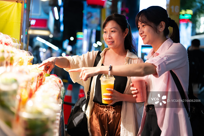 两位亚洲女性游客在台北西门町夜市品尝果汁图片素材