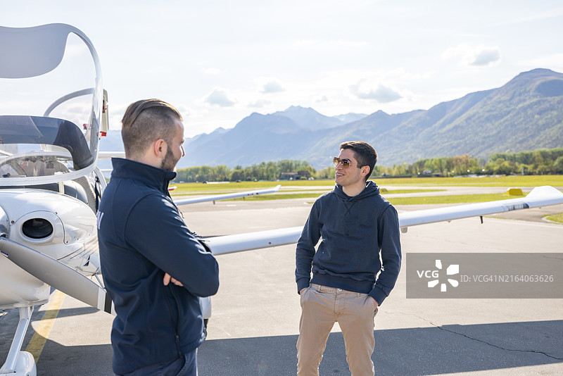 机场内两名男人在轻型飞机旁交谈图片素材