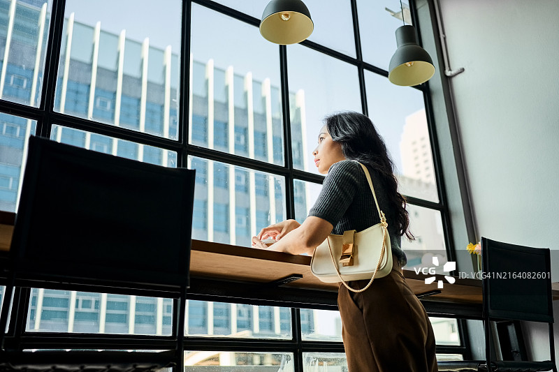 沉思的职业女性凝视着窗外喝咖啡图片素材