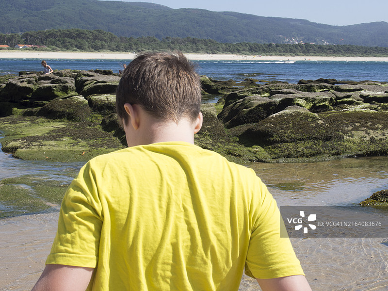 在沙滩上玩耍并眺望海滩地平线的男孩图片素材