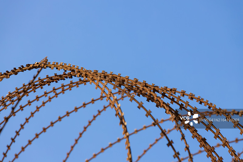 蓝色天空下的生锈铁丝网图片素材