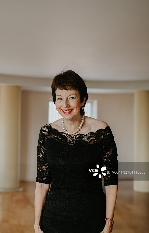 身穿黑色连衣裙，在明亮室内空间自信摆姿势的优雅女人图片素材