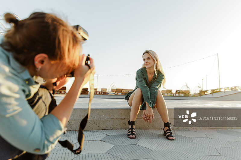 夏季，女摄影师在公园里拍摄一位年轻女人图片素材