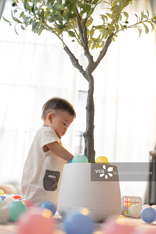 可爱的亚洲男婴玩耍盆栽和彩色塑料玩具图片素材