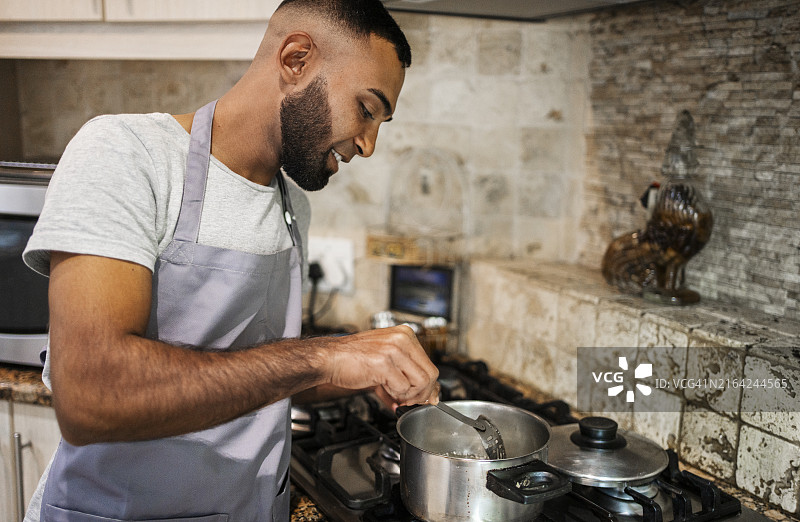斋月期间在炉子上做饭的微笑穆斯林年轻男子图片素材