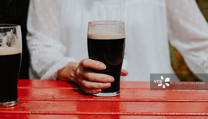 手持一杯烈性黑啤酒的女人特写图片素材